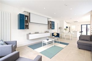 Contemporary them continued from kitchen into living area with wall mounted units housing remote control drop down projector screen and a-v facilities